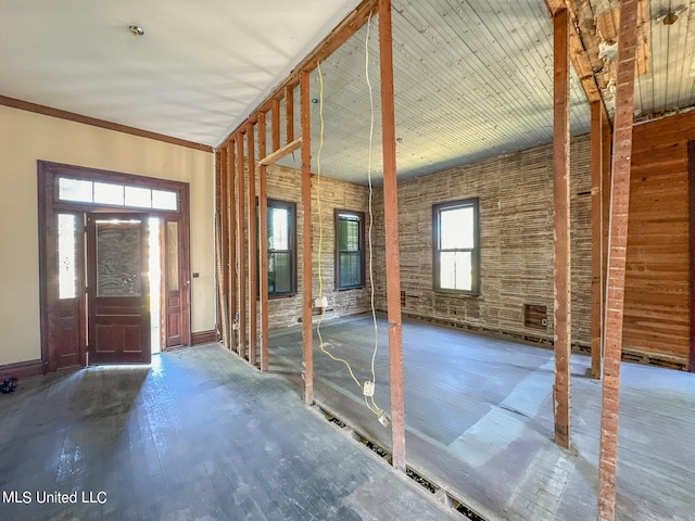 foyer entrance featuring brick wall, ornamental molding, and wood-type flooring