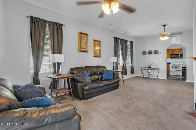 living room with a wealth of natural light, carpet flooring, and ceiling fan