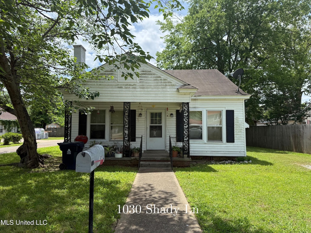 view of front of property with a chimney, a porch, and a shingled roof