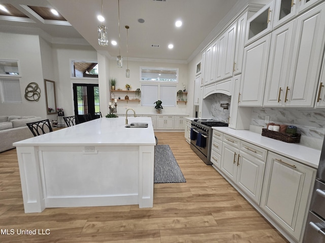kitchen featuring white cabinetry, ornamental molding, a sink, and stainless steel range