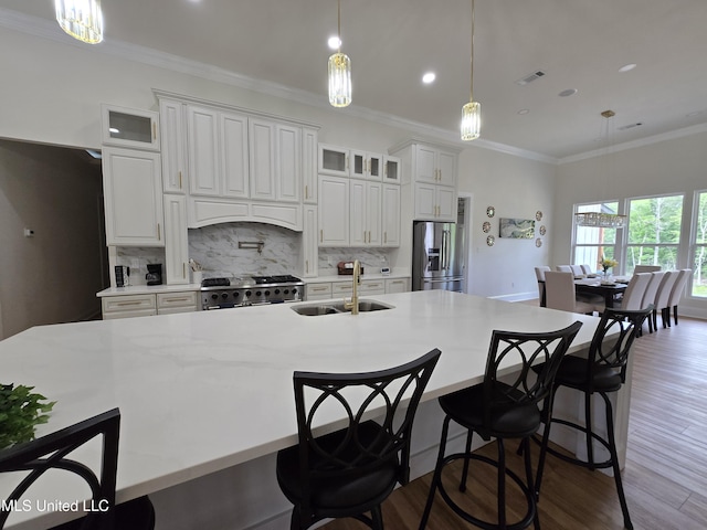 kitchen with stainless steel appliances, a sink, visible vents, backsplash, and ornamental molding