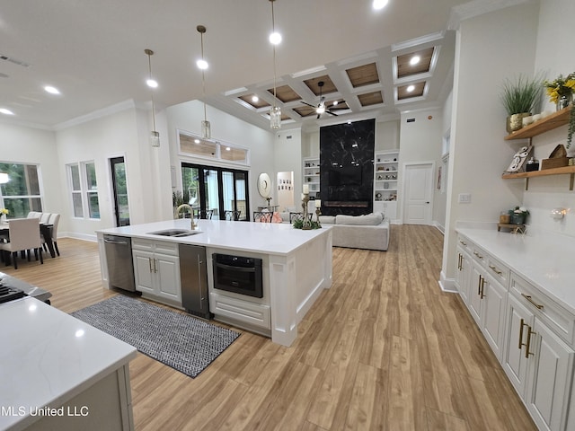 kitchen featuring visible vents, stainless steel dishwasher, a sink, light wood-style flooring, and open floor plan