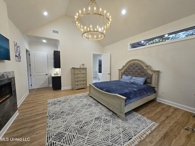 bedroom featuring baseboards, wood finished floors, visible vents, and a notable chandelier