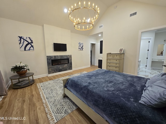 bedroom with high vaulted ceiling, wood finished floors, a chandelier, baseboards, and visible vents