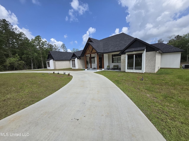 view of front of house featuring roof with shingles, central AC unit, brick siding, curved driveway, and a front yard