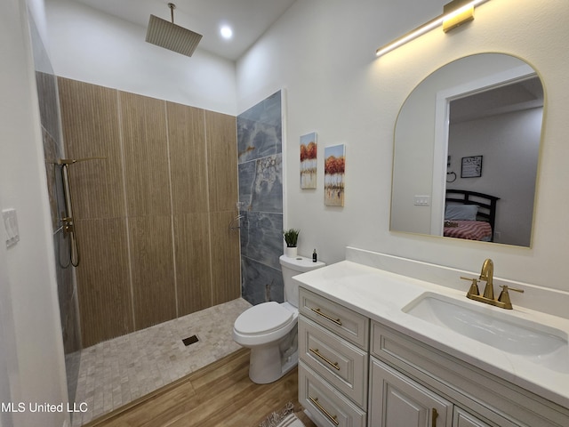 bathroom featuring wood finished floors, ensuite bathroom, vanity, toilet, and tiled shower