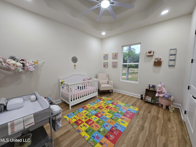 bedroom featuring a nursery area, wood finished floors, and recessed lighting