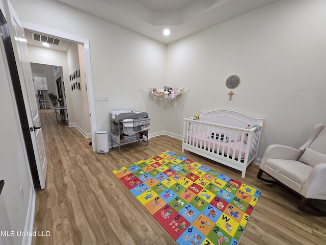 bedroom featuring visible vents, recessed lighting, baseboards, wood finished floors, and a crib