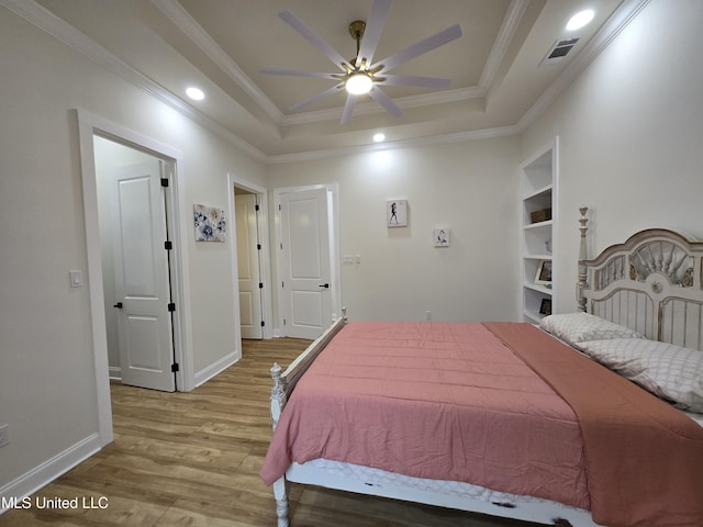 bedroom with crown molding, wood finished floors, visible vents, and a raised ceiling