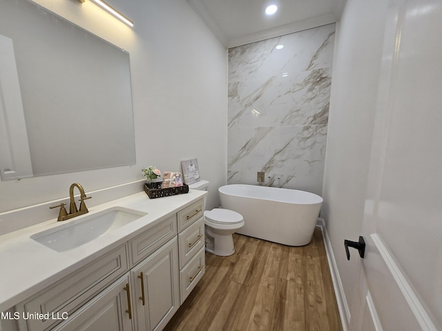bathroom featuring wood finished floors, vanity, a freestanding bath, toilet, and recessed lighting