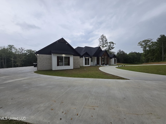 view of front of home with board and batten siding, curved driveway, and a front yard