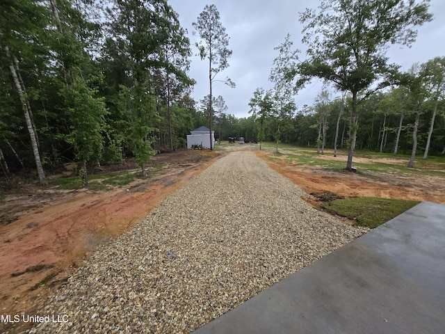 view of street with driveway and a forest view