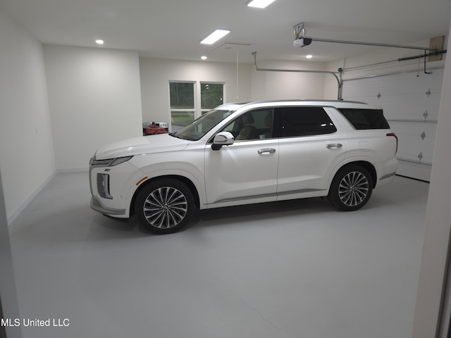 garage with baseboards, a garage door opener, and recessed lighting