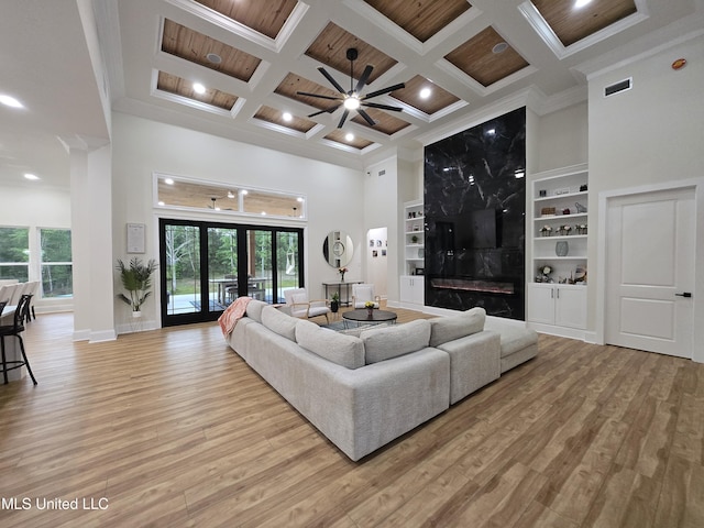 living room with light wood-style flooring, built in shelves, and coffered ceiling