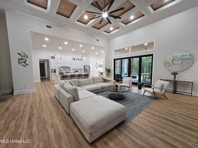 living area with visible vents, baseboards, coffered ceiling, a high ceiling, and ceiling fan