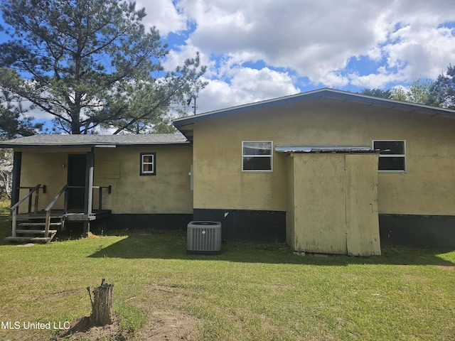 rear view of house featuring cooling unit and a yard