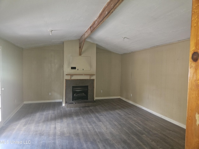 unfurnished living room with wood finished floors, a fireplace with raised hearth, wooden walls, and baseboards