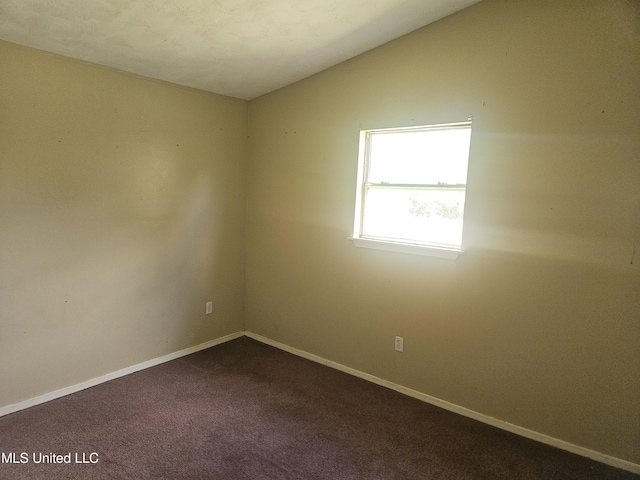 empty room with baseboards, dark carpet, and lofted ceiling