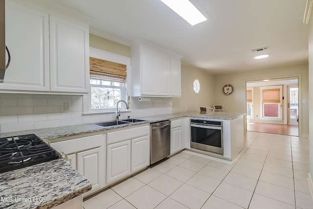 kitchen featuring sink, appliances with stainless steel finishes, backsplash, white cabinets, and kitchen peninsula