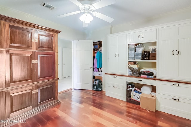 mudroom with ceiling fan, built in desk, ornamental molding, and wood-type flooring