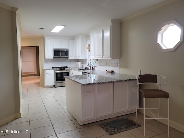 kitchen with stainless steel appliances, kitchen peninsula, decorative backsplash, and white cabinets