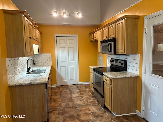 kitchen featuring light stone countertops, appliances with stainless steel finishes, decorative backsplash, and sink