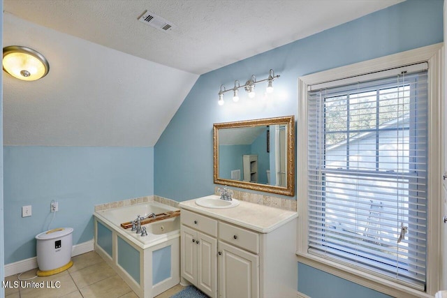 bathroom featuring vanity, a textured ceiling, tile patterned floors, lofted ceiling, and a bathtub