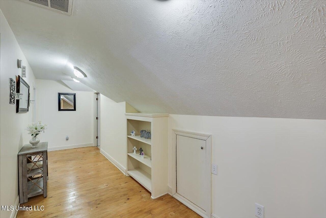 bonus room featuring a textured ceiling, lofted ceiling, and light wood-type flooring