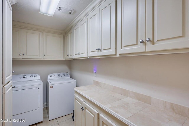 laundry area with light tile patterned floors, a textured ceiling, cabinets, and washing machine and clothes dryer