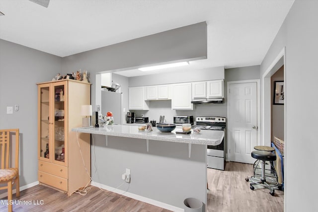 15820 Big Ridge Rd, Biloxi, MS 39532 - kitchen with stainless steel range with electric cooktop, a peninsula, light wood-style floors, under cabinet range hood, and white cabinetry