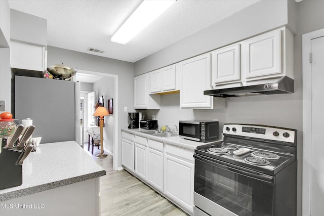 15820 Big Ridge Rd, Biloxi, MS 39532 - kitchen with electric range, under cabinet range hood, freestanding refrigerator, white cabinets, and a textured ceiling