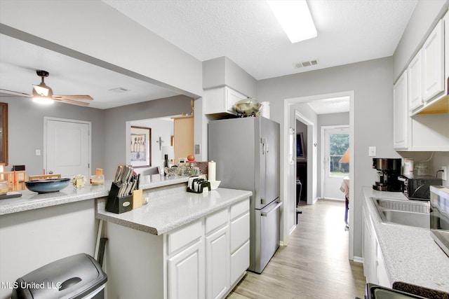 15820 Big Ridge Rd, Biloxi, MS 39532 - kitchen featuring freestanding refrigerator, light wood finished floors, white cabinetry, and ceiling fan