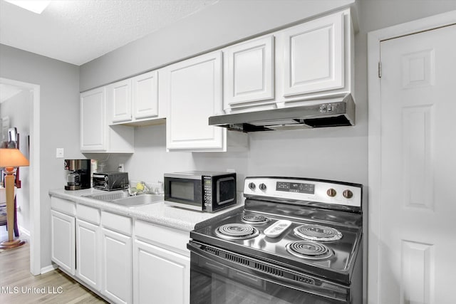 15820 Big Ridge Rd, Biloxi, MS 39532 - kitchen featuring range with electric stovetop, under cabinet range hood, white cabinetry, a sink, and a textured ceiling