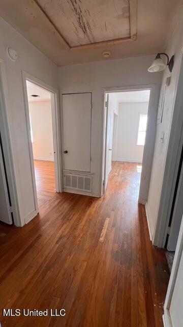 hallway with visible vents, baseboards, and wood finished floors