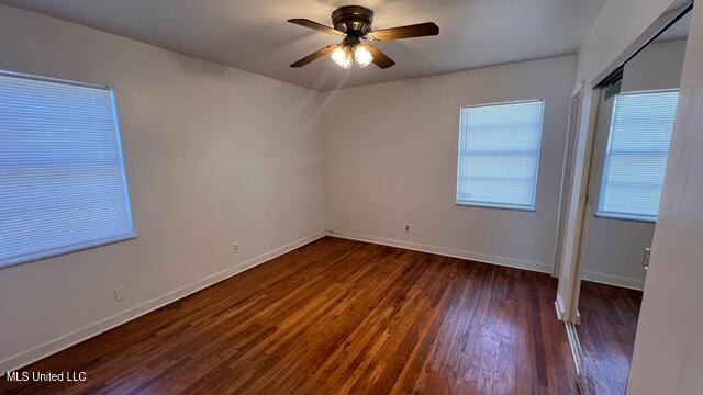 empty room featuring ceiling fan, baseboards, and wood finished floors