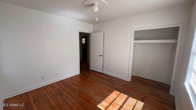 unfurnished bedroom featuring a closet, baseboards, and wood finished floors