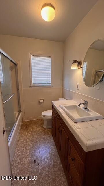 full bathroom featuring vanity, toilet, and combined bath / shower with glass door