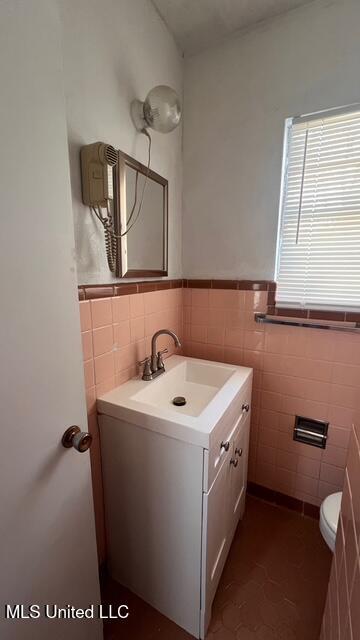 bathroom with vanity, tile walls, toilet, and a wainscoted wall