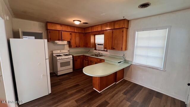 kitchen with white appliances, a peninsula, a sink, light countertops, and brown cabinets