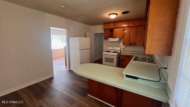 kitchen with white appliances, a peninsula, a sink, light countertops, and brown cabinets