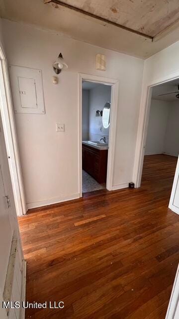 hallway featuring a sink, baseboards, and wood-type flooring