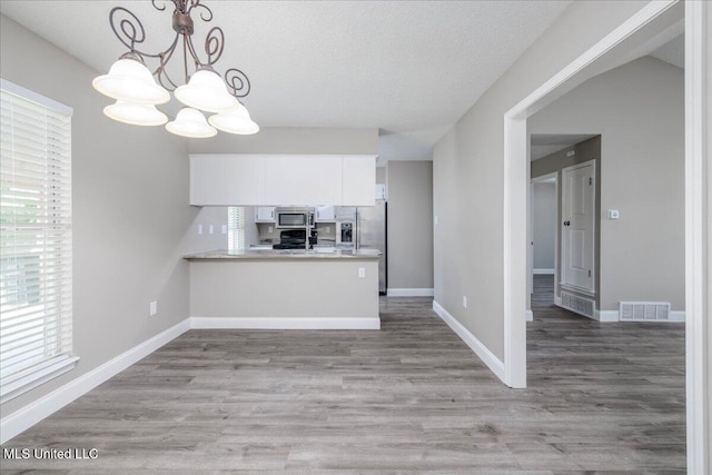 6967 Green Way Cv, Olive Branch, MS 38654 - kitchen featuring appliances with stainless steel finishes, white cabinetry, a chandelier, light countertops, and a peninsula