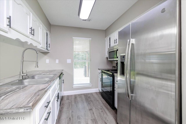 6967 Green Way Cv, Olive Branch, MS 38654 - kitchen featuring appliances with stainless steel finishes, light wood-style flooring, light countertops, and white cabinetry