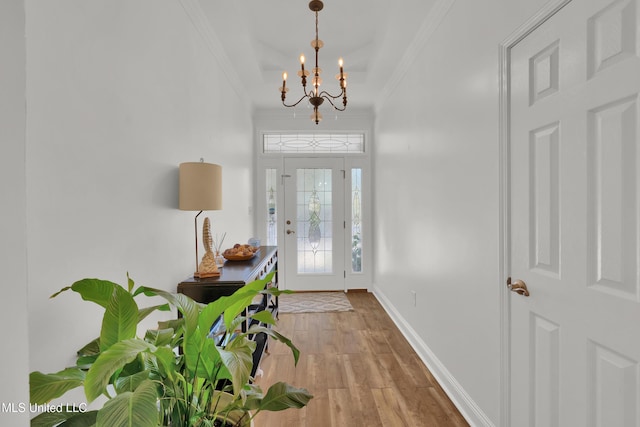 foyer with light hardwood / wood-style flooring, ornamental molding, and a notable chandelier