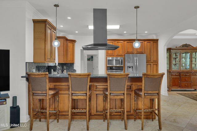 kitchen with island exhaust hood, appliances with stainless steel finishes, hanging light fixtures, and a breakfast bar area