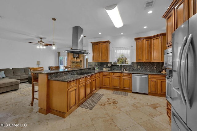 kitchen featuring sink, stainless steel appliances, kitchen peninsula, island range hood, and a breakfast bar