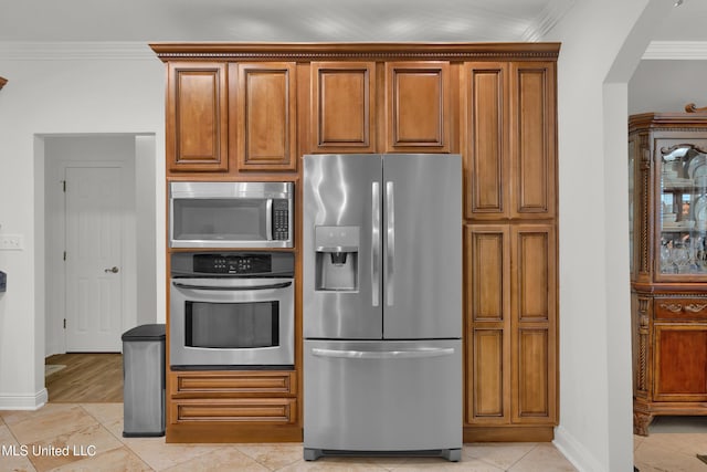 kitchen featuring light tile patterned floors, stainless steel appliances, and ornamental molding