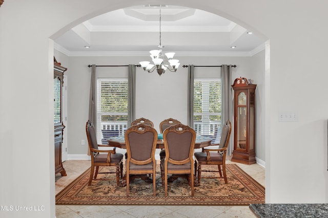 tiled dining space featuring ornamental molding, a tray ceiling, and a notable chandelier