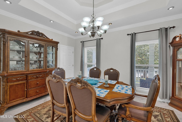 dining area with light tile patterned floors, a tray ceiling, an inviting chandelier, and ornamental molding