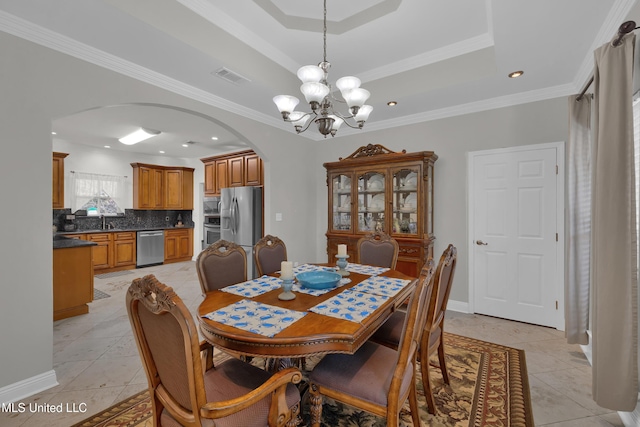 dining room featuring a tray ceiling, light tile patterned floors, a chandelier, and ornamental molding